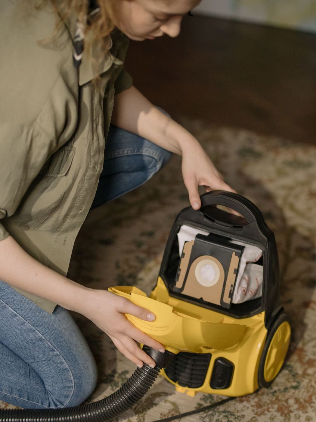 Person emptying a vacuum cleaner on a rug