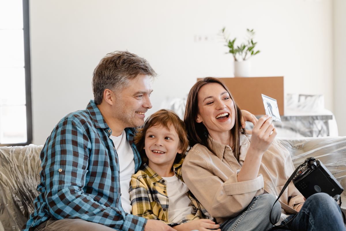 Family relaxing on a couch with moving boxes behind them